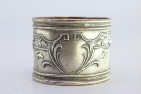 Argola de guardanapo em prata com motivos florais relevados envolvendo cartela para monograma.